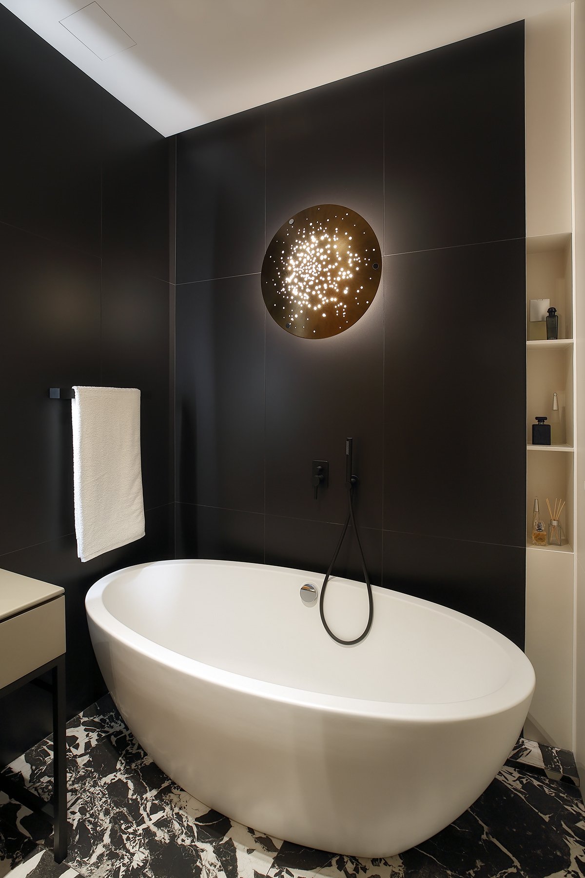 Freestanding bathtub against a dark accent wall.