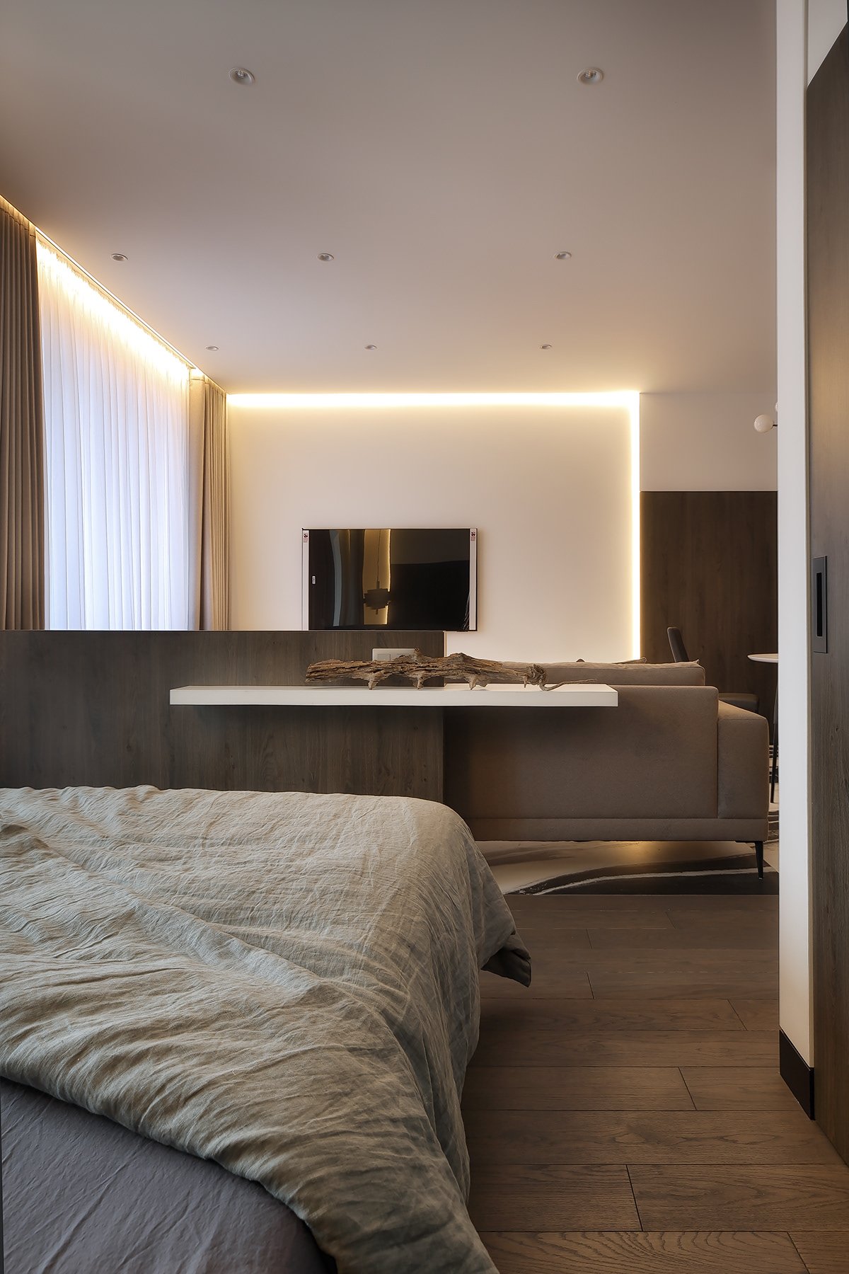 Bedroom with a backlit ceiling cove and timber flooring.