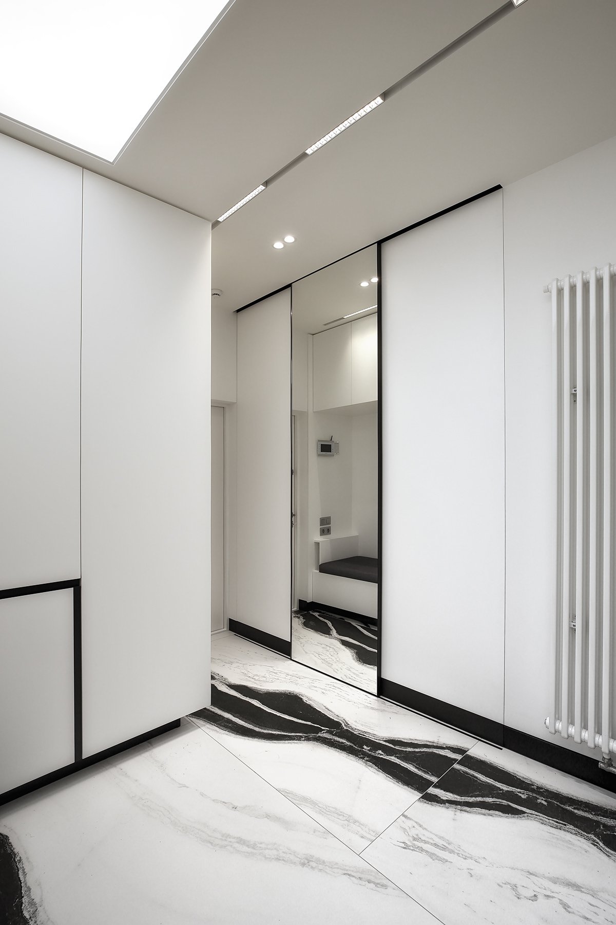 Entry corridor with black and white marble patterned flooring and amber lit door.