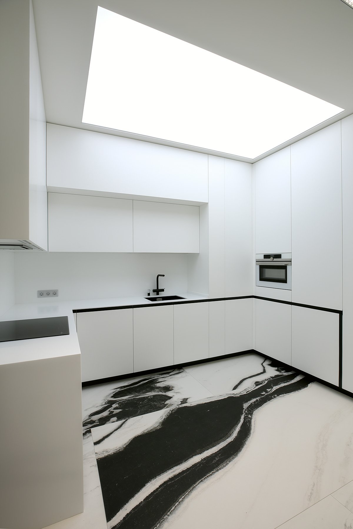 Kitchen beneath a skylight, with black and white marble patterned flooring.