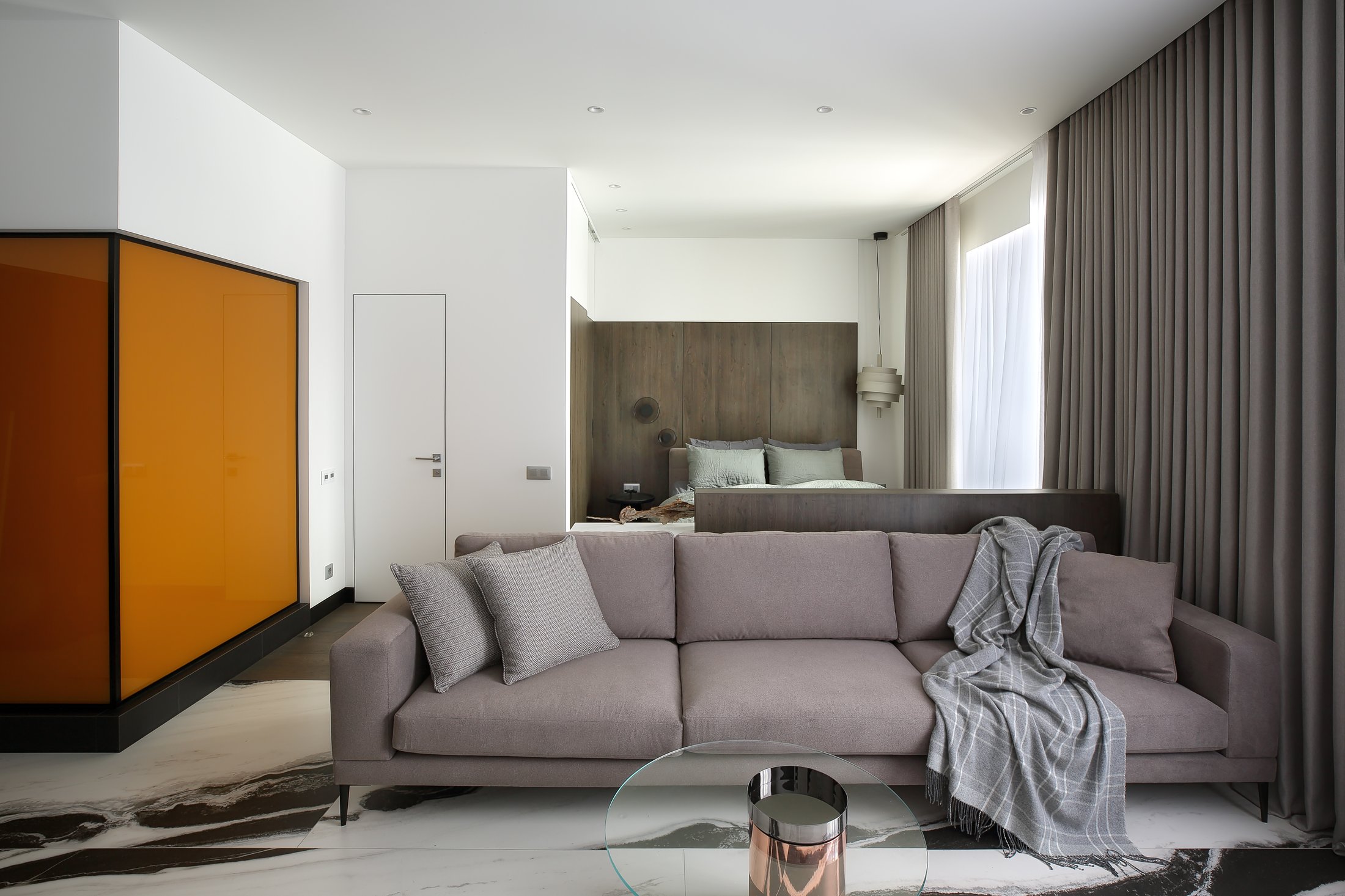Living room with an amber feature wall, sofa and glass coffee table.