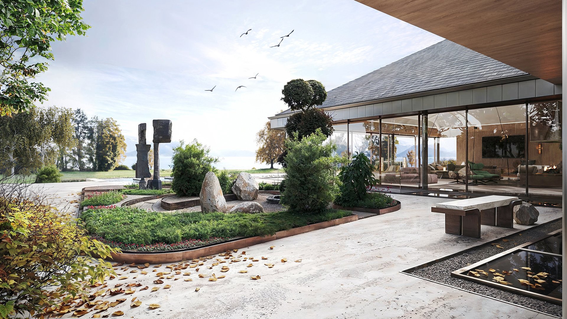 Garden at dusk with sculptural stone pieces and lake terrace beyond.